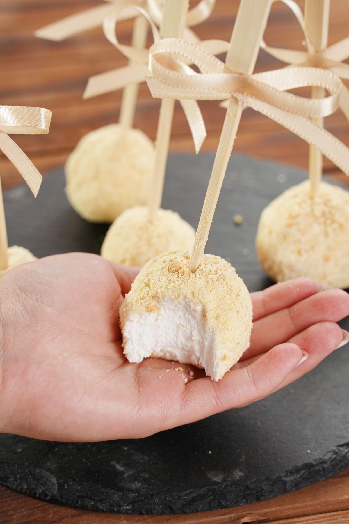 A bite of White Chocolate Cheesecake Pops in hand