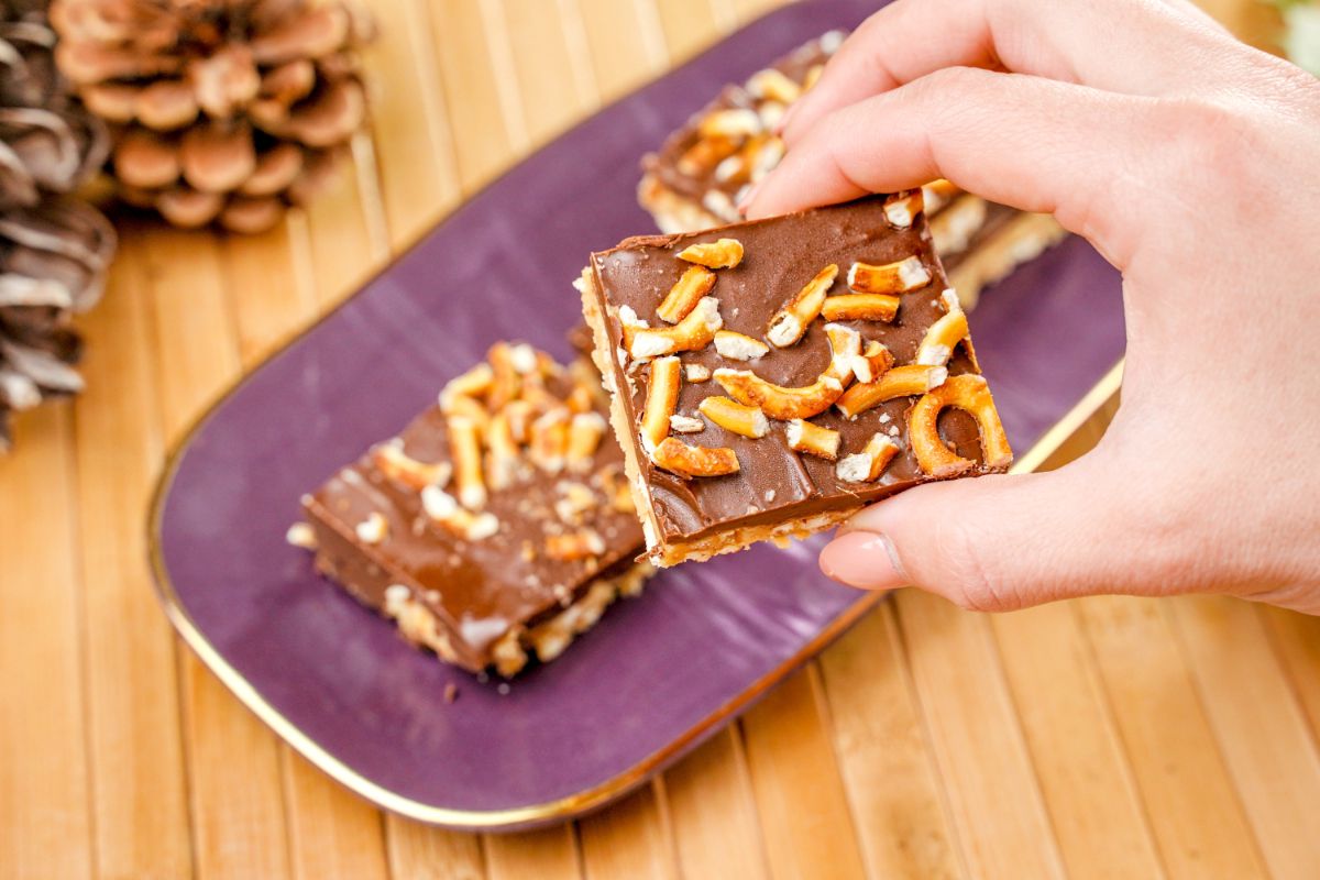 A piece of No-Bake Pretzel Peanut Butter Chocolate Bars in fingers