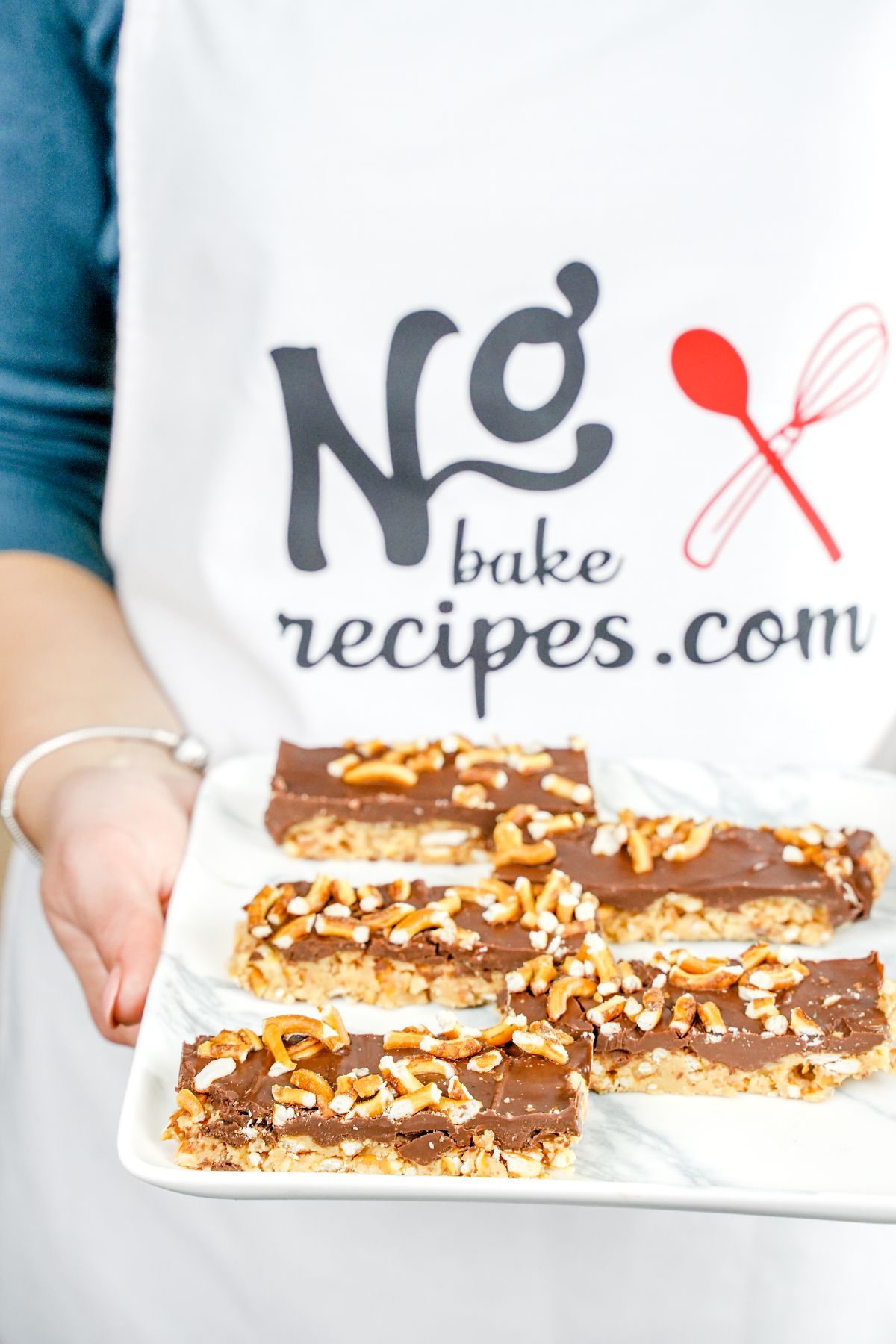 No-Bake Pretzel Peanut Butter Chocolate Bars served on a plater in hand