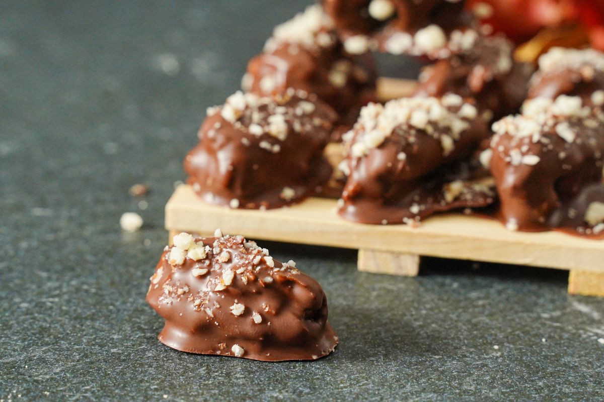 Chocolate Covered Peanut Stuffed Dates served on a wooden rack