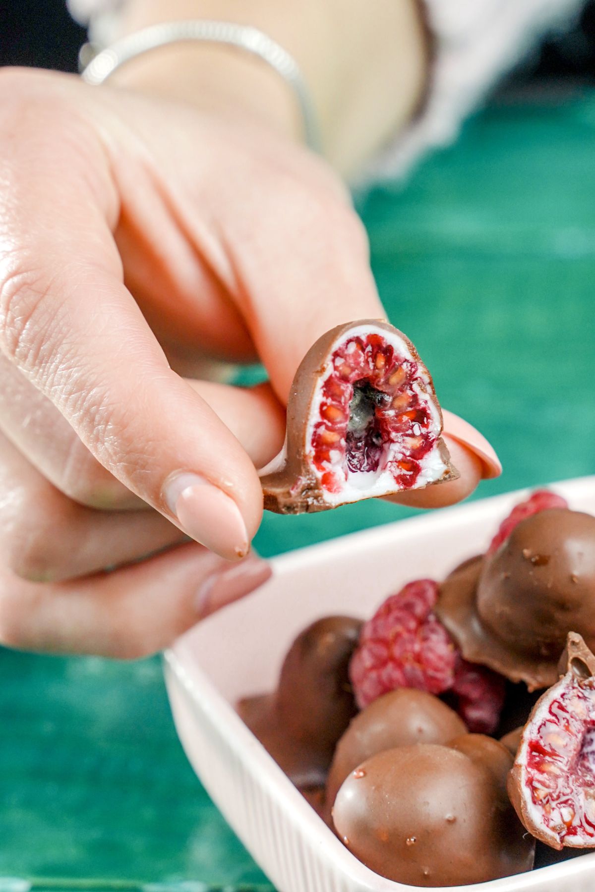 Half cut Chocolate-Dipped Raspberries in fingers