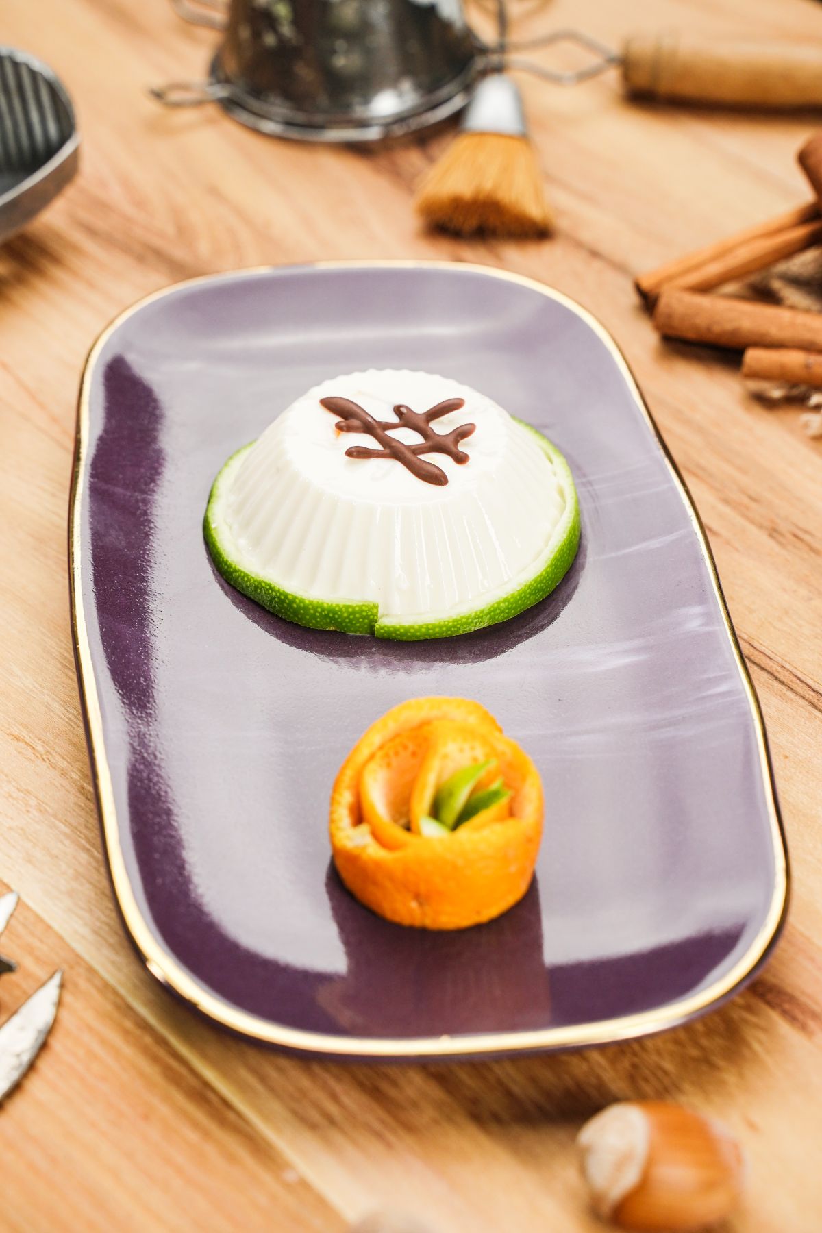 Orange Panna Cotta served on a purple plater and decorated with orange peel