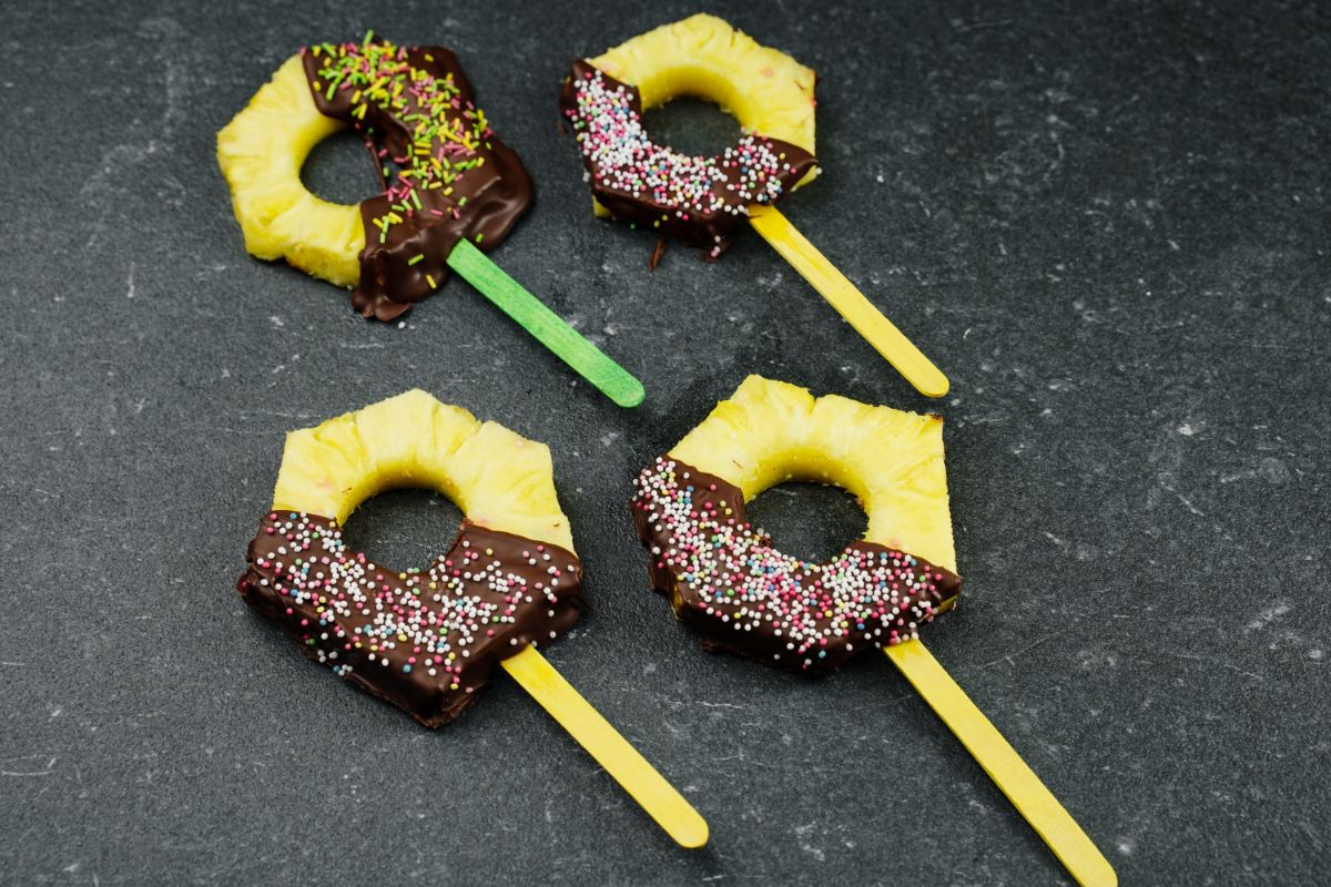 Chocolate Coated Pineapple Pops on  black surface