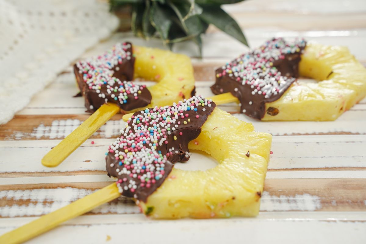 Chocolate Coated Pineapple Pops kept on a wooden plank