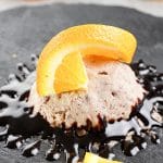 scoop of banana chocolate ice cream on a plate with chocolate and orange slices