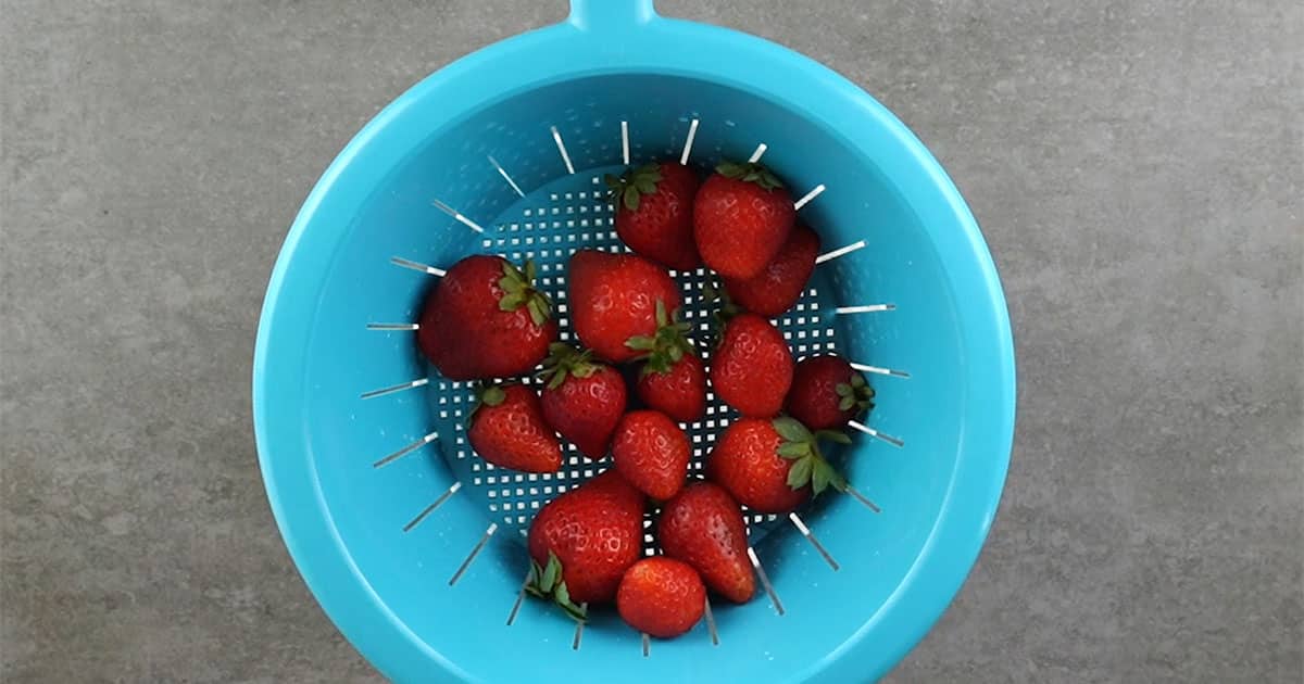 straining strawberries to make boozy chocolate covered strawberries