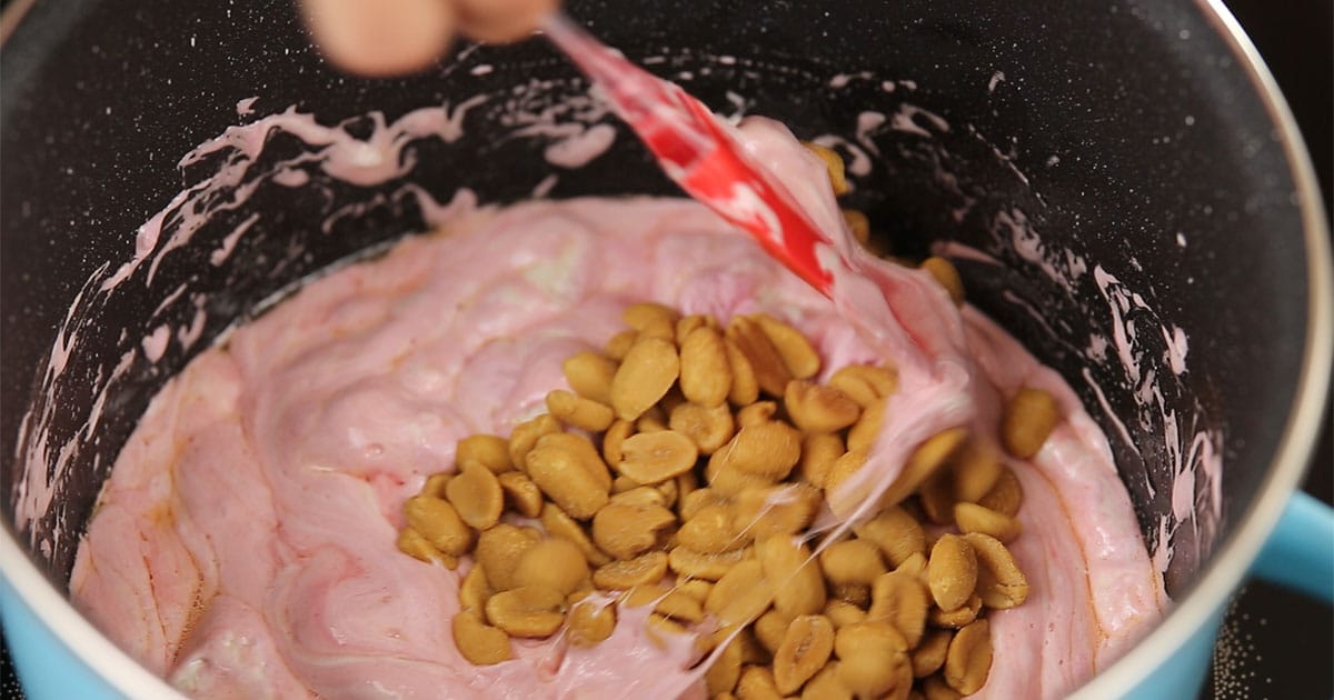 stirring a mixture of peanuts and marshmallow to make rocky road popcorn balls