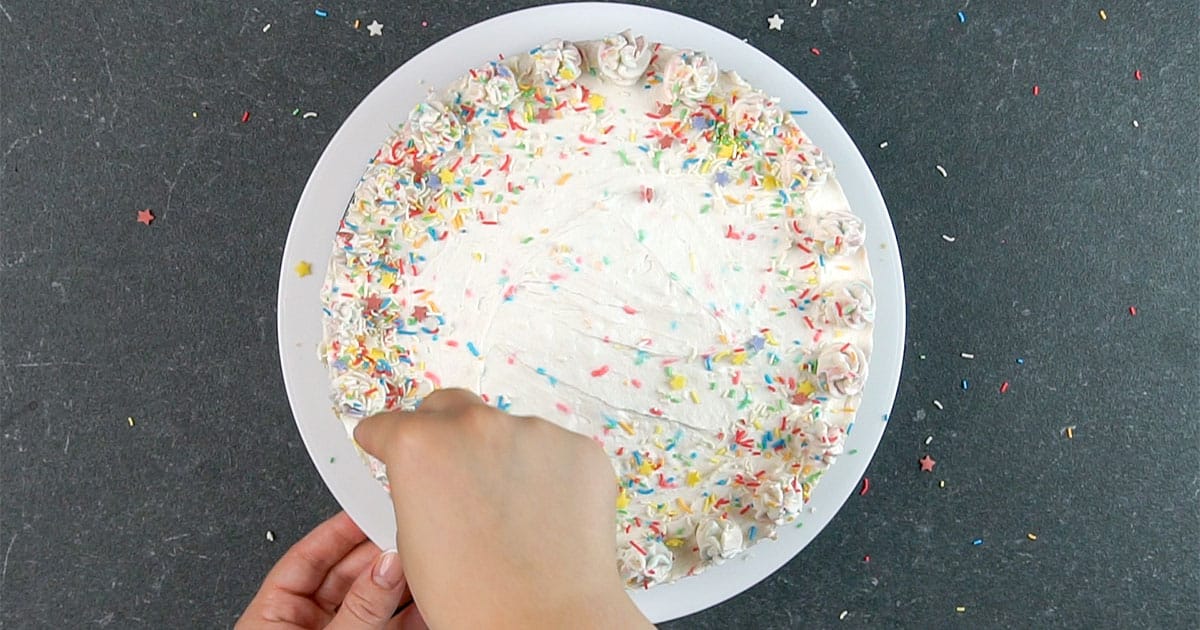 overhead view of adding sprinkles to the top of a Funfetti Cheesecake no-bake cheesecake