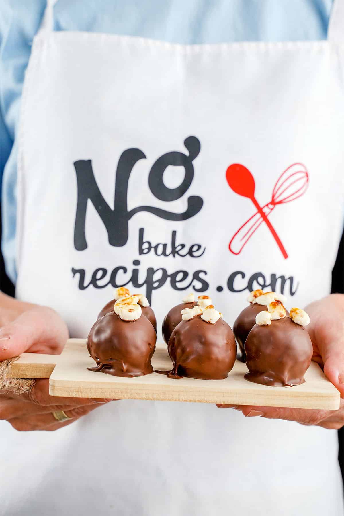 hands holding a wood board of S'mores truffles