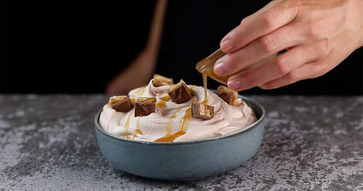 caramel being drizzled over Snickers dip