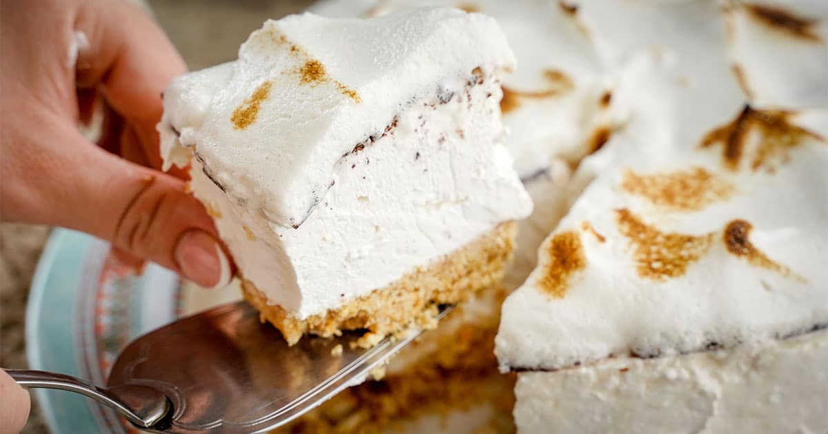 slice of no-bake s'mores cheesecake being cut from the cake