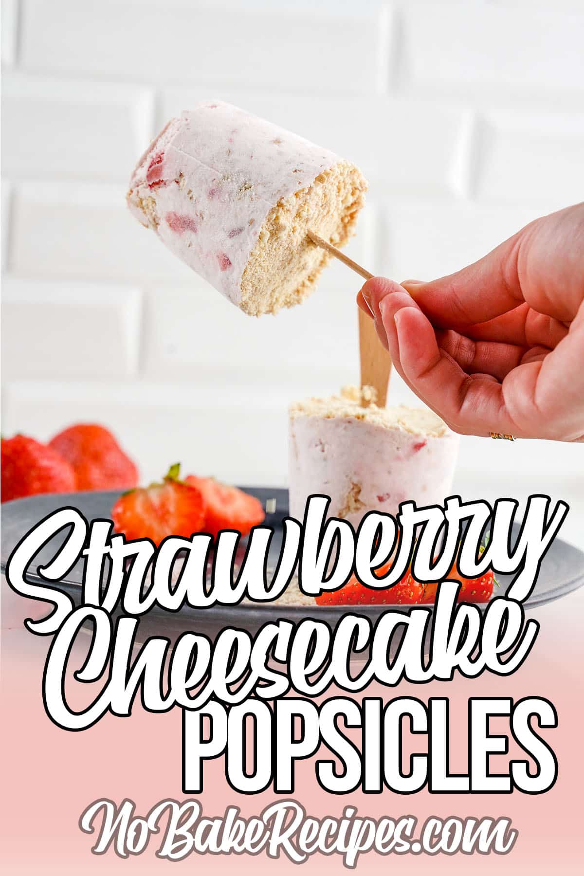 hand holding up a strawberry popsicle with text which reads strawberry cheesecake popsicles