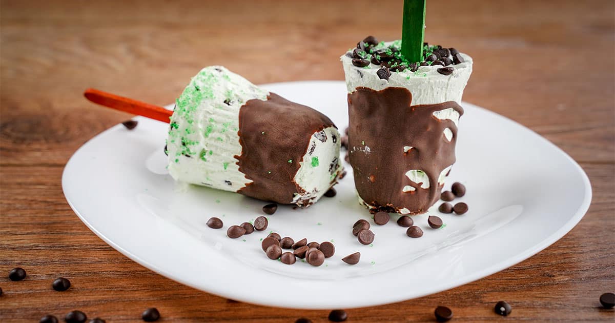 two Mint chocolate chip popsicles on plate.