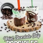 mint chocolate chip popsicles on wood plat with chocolate chips scattered.