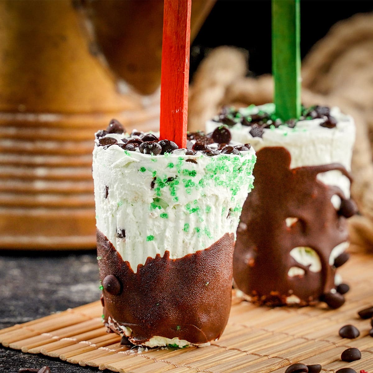 side view of mint chocolate chip popsicles red stick in front.